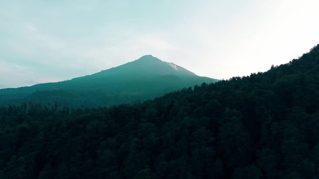 Aerial view of a Lawu mountain peak surrounded by dense green forest under a bright morning sky, in Tawangmangu, Central of Java, on Saturday, October 25, 2025.	