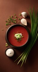 Red soup topped with cream, chives, in black bowl on brown
