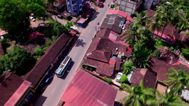 Aerial View of Small Town Street With Bus and Red-Roof Buildings in goa. day time, tracking shot, drone shot, 4k.