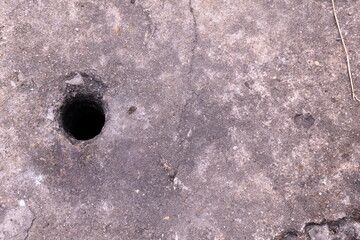 Close-Up View of a Round Hole in Weathered Concrete Surface with Textured Gray Finish and Natural Elements