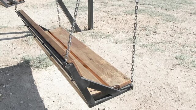 empty swing is swinging on chains slow motion
