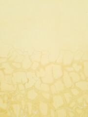 Fototapeta premium Weathered Yellow Plaster Wall Texture with Cracked Pattern. Concept of Skin Barrier Metaphor, Raw Industrial Aesthetics, and Structural Repair for Eco-Friendly Branding and Architectural Design