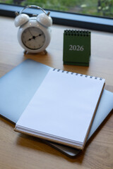 Blank spiral notebook on silver laptop with wooden desk background, perfect for work planning, note-taking, creativity digital workspace themes.