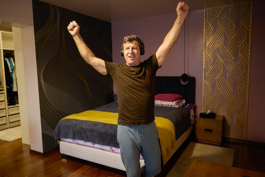 Middle-aged man relaxes by listening to music at home - Powered by Adobe
