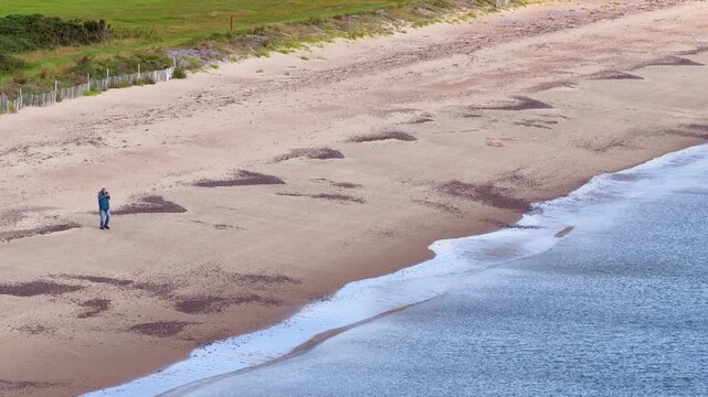 Person Walking Alone on Rosemarkie Sandy Beach Shoreline