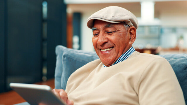 Tablet, smile and senior man on sofa in home with connection, social media or blog post. Retirement, digital technology and elderly person in living room for reading news headline on app in house. - Powered by Adobe