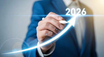 Businessman's hand drawing glowing upward arrow with 2026, symbolizing future business growth and success goals