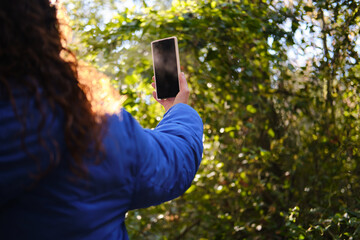 Woman holding smartphone taking picture in nature. unrecognizable person