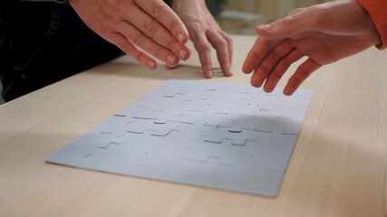 Assembling puzzle piece by hand shows collaboration and teamwork as two people complete jigsaw and form connection through handshake and agreement over puzzle solution and partnership at desk meeting