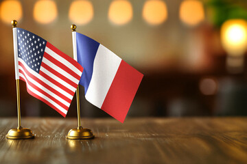 United States USA and France small desk flags on wooden table - diplomatic relations concept with copy space