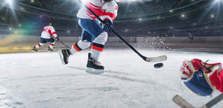 Ice hockey rink arena with professional player shooting the puck with hockey stick.  Focus on the puck. Hockey player in action. Ice.