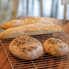 Homemade artisan bread on cooling rack with rustic lighting, freshly baked round loaves and baguettes in warm kitchen setting