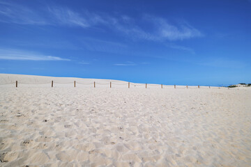 Sand dunes by the sea in Leba, Slowinski National Park, Poland. Safety barriers constructed of wooden posts and ropes. Beautiful desert landscape