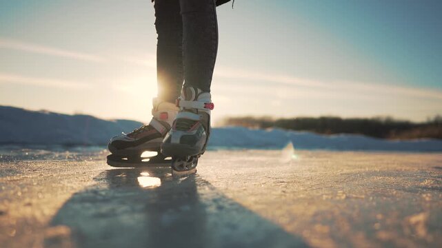 Skating on frozen lake at sunset, closeup of skate boot and blade gliding across ice with reflection on surface, winter outdoor activity near natural rink with warm light and quiet atmosphere