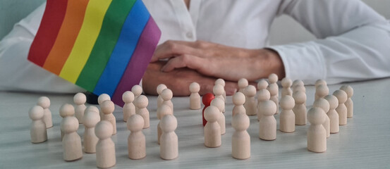 Person Holding Rainbow Pride Flag With Wooden People Figurines