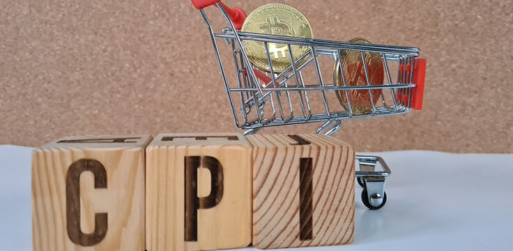 Miniature Shopping Cart Filled With Gold Coins Resting on Wooden Blocks Spelling CPI