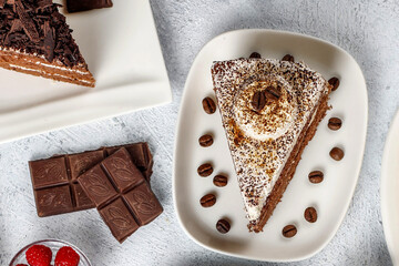 Gourmet Tiramisu Cake Slice with Coffee Beans and Chocolate Bars on a Textured Surface