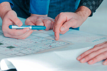 Hands of Two Engineers Reviewing Architectural Blueprint Plans with a Marker