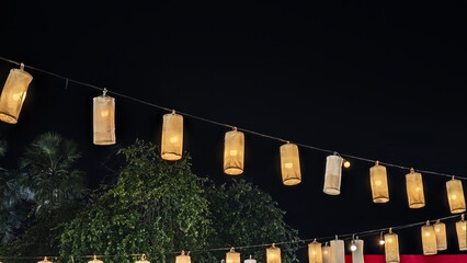 Rows of glowing rectangular paper lanterns strung across a street at night