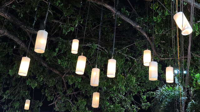 Rows of glowing rectangular paper lanterns strung across a street at night