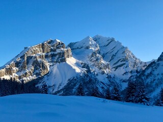 Breathtaking Swiss mountain landscape in winter with clear morning light, deep fresh snow under a blue sky, Kandersteg, Sunnbüel, Bernese Oberland, Switzerland
