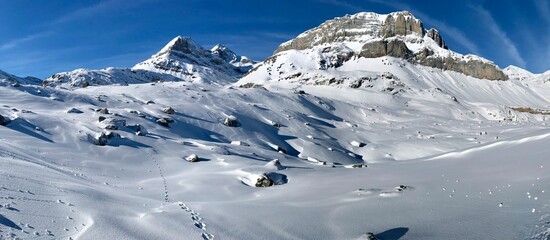 A breathtaking panoramic winter mountain landscape in the Swiss Alps near Kandersteg, covered in deep, untouched snow, Bernese Oberland, Switzerland
