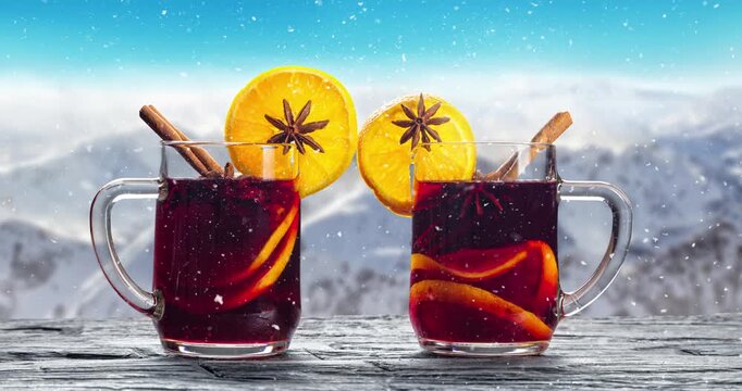 Hot mulled wine with spices and Christmas decor on a wooden table, with snowy mountain backdrop and gentle slow-motion snowfall. Cozy winter atmosphere, perfect holiday background.