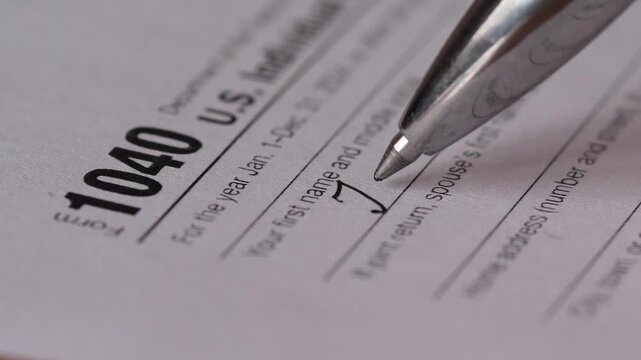 Close-up of Man Filling IRS 1040 Tax Form with Pen, Personal Income Tax Payment Concept
