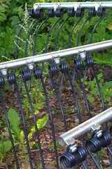 Fototapeta premium Agricultural Harrow Tines Close-up in Greenery