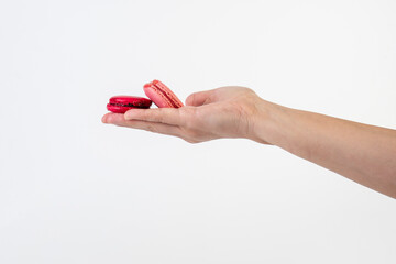 Pink and red macarons in hand on white background