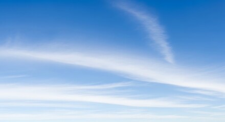 Clear blue sky with wispy white cirrus clouds stretching across, creating a serene and expansive atmosphere above.