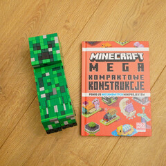 Naklejka premium Minecraft Creeper figure and Mega Kompaktowe Konstrukcje book on wooden surface