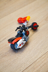 Obraz premium A cool Lego motorcycle toy with a red and black color scheme on a wooden surface