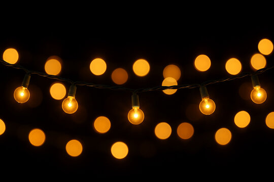Warm christmas string lights with golden bokeh on black background