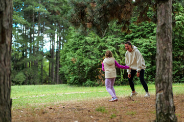 Obraz premium Mother and daughter playing and laughing in a pine forest