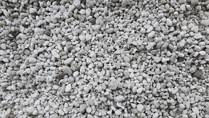 A surface of small gray and white pebbles. Shows the natural rough, porous texture. Ideal background for design related to nature, construction materials, or gardening.