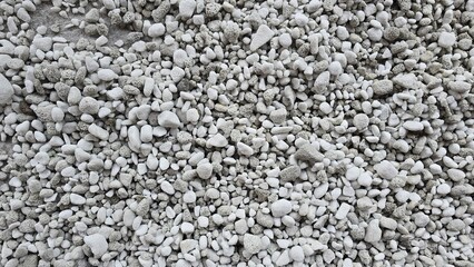 A surface of small gray and white pebbles. Shows the natural rough, porous texture. Ideal background for design related to nature, construction materials, or gardening.