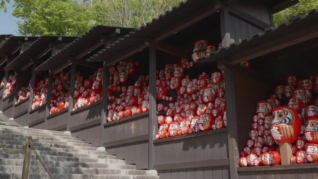 Big red daruma dolls stacked together on a sunny day in Katsuoji Temple, Osaka, Japan.