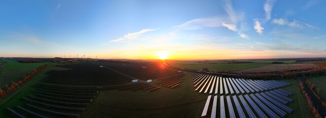 Aerial view of solar panels gleaming under the vibrant sunset near Newmarket, England, United Kingdom.