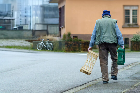homme &acirc;g&eacute; marchant dans la rue avec cageots dans ses mains