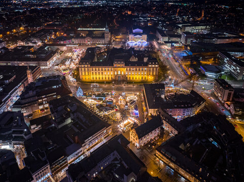 Aerial view of lights illuminating the Darmstadt Christmas Market next to the Schloss Darmstadt, contrasting with the dark city, Darmstadt, Hessen, Germany.