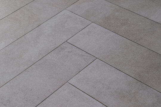 Grey rectangular tile texture in herringbone pattern imitating natural stone