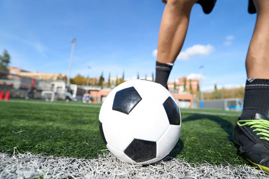 Football player standing on turf field with soccer ball