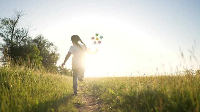 girl running through tall grass toward bright sun in summer field while child holds colorful pinwheel playful and carefree outdoor energy showing running child among green grass under clear sky