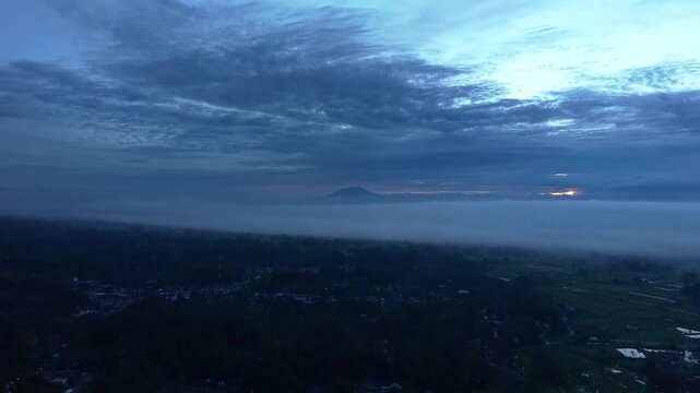 Aerial view of the misty mountains, with the landscape shrouded in a thick blanket of fog, creating an ethereal scene, Klaten Regency, Central Java, Indonesia.