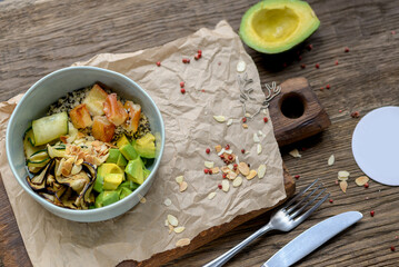 bowl of avocado, eel and quinoa porridge with vegetables in a plate on a board on a table with food decor