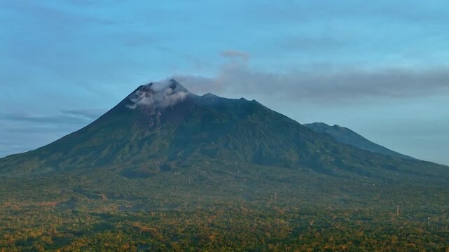 Aerial view of the majestic Mount Merapi and Mount Merbabu volcanoes rising above the lush green landscape, Klaten Regency, Central Java, Indonesia.