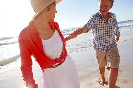 Love, date and holding hands with couple at beach for summer vacation, romance and connection. Bonding, anniversary getaway and walk with mature man and woman outdoor for holiday, marriage and travel - Powered by Adobe