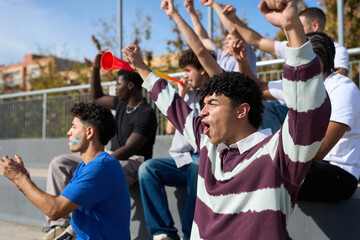 Young men cheering sports event from bleachers