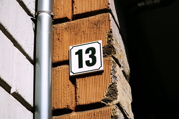 Num&eacute;ro 13. Plaque de num&eacute;ro de rue sur vieux mur de pierre abim&eacute;.